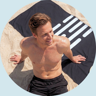 2 mænd og 1 kvinde ligger på håndklæder på stranden.